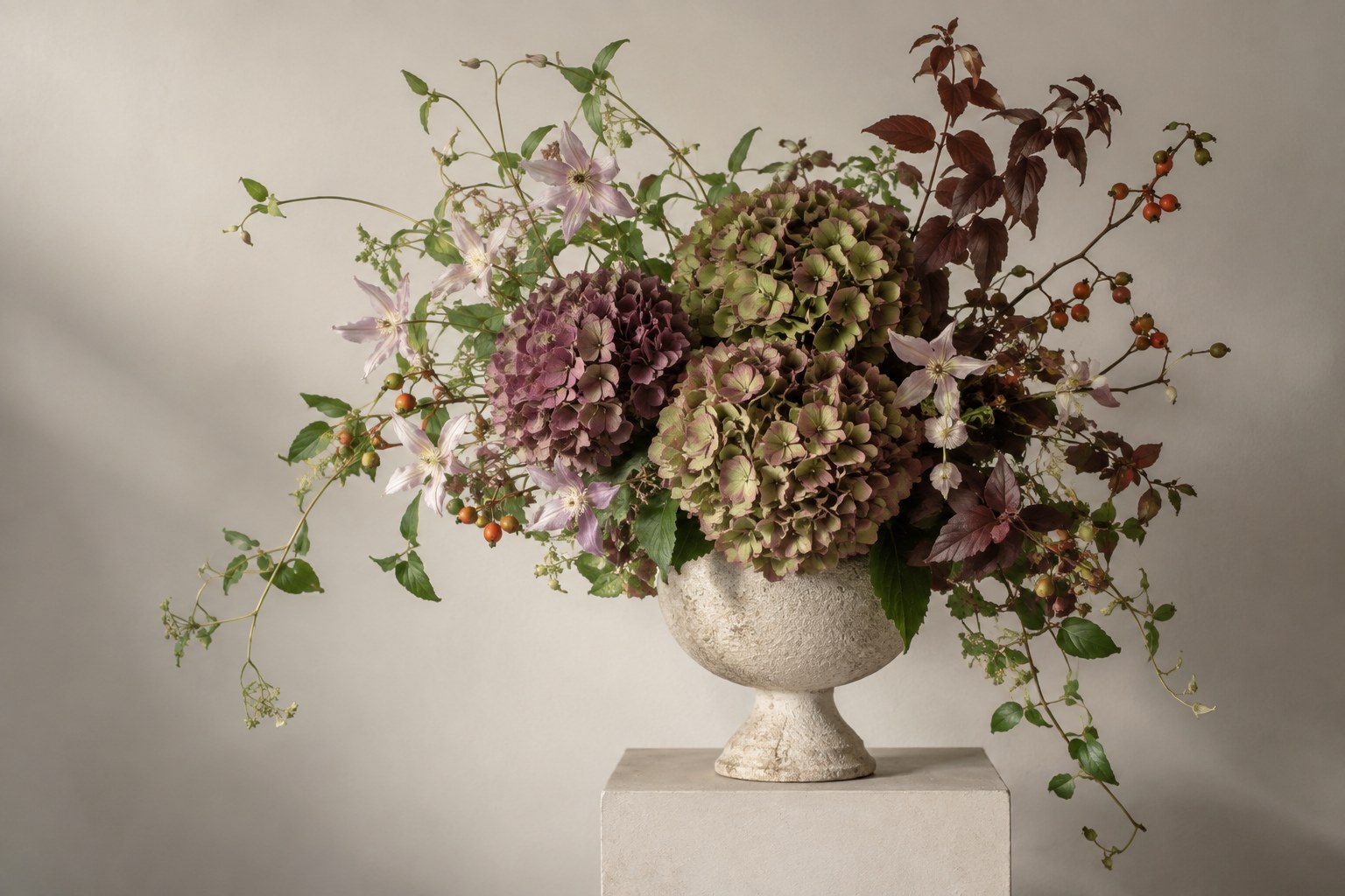 Seasonal antique hydrangeas and trailing vines in a stone vase